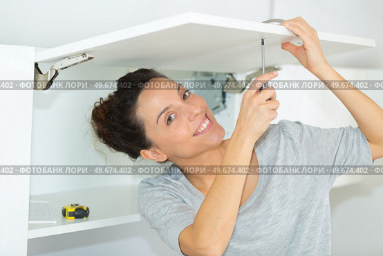 woman fixing a cabinet door. Стоковое фото, агентство Ingram Publishing / Фотобанк Лори