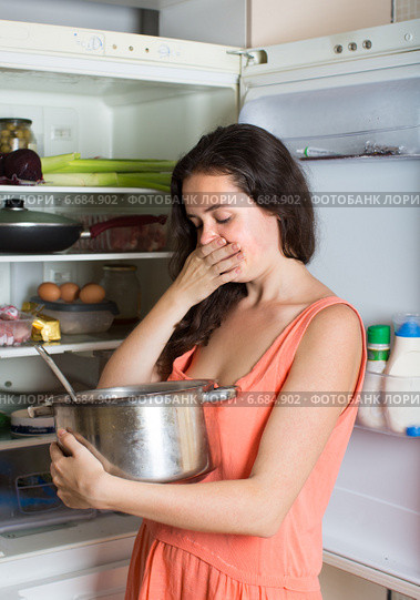 woman holding foul food near refrigerator. Стоковое фото, фотограф Яков Филимонов / Фотобанк Лори