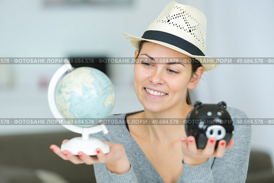woman holding globe and piggy bank wearing sunhat. Стоковое фото, агентство Ingram Publishing / Фотобанк Лори