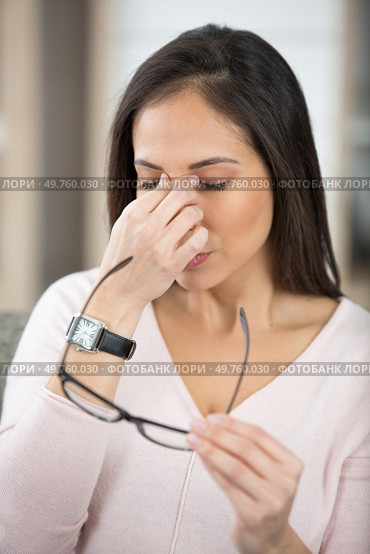 woman holding spectacles and rubbing the bridge of her nose. Стоковое фото, агентство Ingram Publishing / Фотобанк Лори