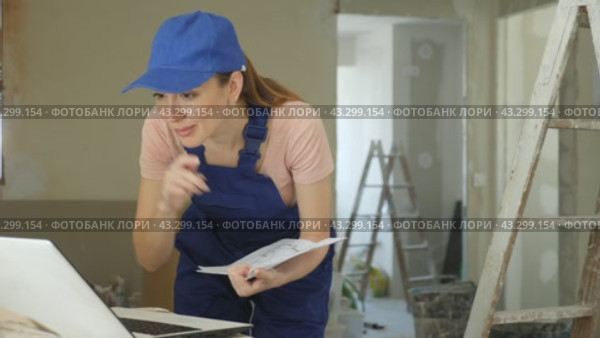 Woman in blue overalls checking completed construction work on the drawing. Стоковое видео, видеограф Яков Филимонов / Фотобанк Лори