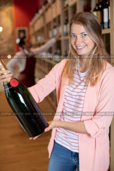woman in off-license holding a magnum of champagne. Стоковое фото, агентство Ingram Publishing / Фотобанк Лори