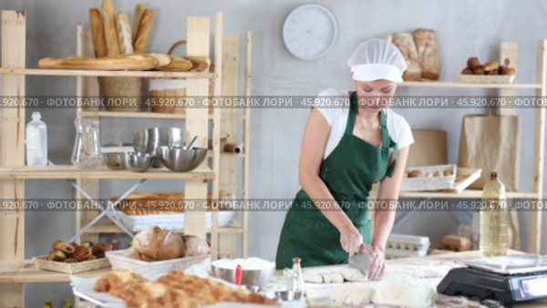 Woman is standing with cutter in her hands, working with dough, divide raw dough. Стоковое видео, видеограф Яков Филимонов / Фотобанк Лори