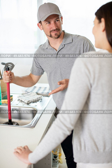 woman looking at male plumber cleaning clogged sink. Стоковое фото, агентство Ingram Publishing / Фотобанк Лори