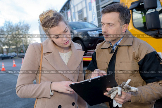 woman looking at paperwork held by breakdown recovery driver. Стоковое фото, агентство Ingram Publishing / Фотобанк Лори