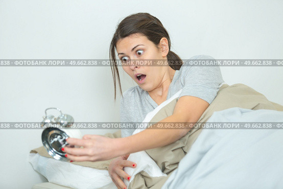woman oversleeping and realising time on alarmclock. Стоковое фото, агентство Ingram Publishing / Фотобанк Лори