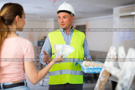 Woman owner of apartment giving wage to man construction painter. Стоковое фото, фотограф Яков Филимонов / Фотобанк Лори