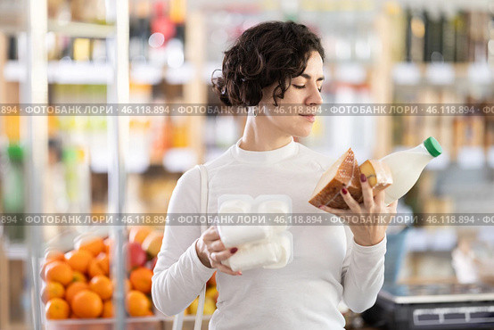 Woman picked up lot of varied food, and with armful of groceries, they choose something else. Стоковое фото, фотограф Яков Филимонов / Фотобанк Лори