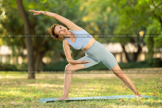 Woman practicing yoga in garden, performing Anjaneyasana, or Crescent Moon Pose. Стоковое фото, фотограф Яков Филимонов / Фотобанк Лори
