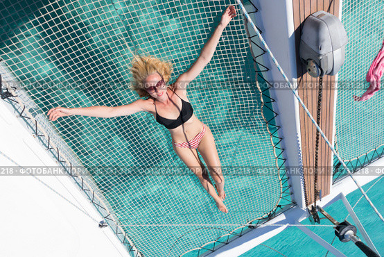 Woman relaxing on a summer sailing cruise,lying in hammock of luxury catamaran near picture perfect white sandy beach on Spargi island in Maddalena Archipelago, Sardinia, Italy. Стоковое фото, фотограф Matej Kastelic / Фотобанк Лори