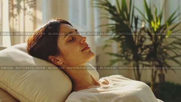Woman relaxing on couch enjoying sunlight, peaceful home atmosphere. Стоковое AI-видео, аниматор Юрий Поздников / Фотобанк Лори