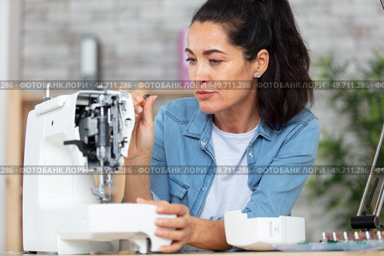 woman repairing dismantled sewing machine. Стоковое фото, агентство Ingram Publishing / Фотобанк Лори