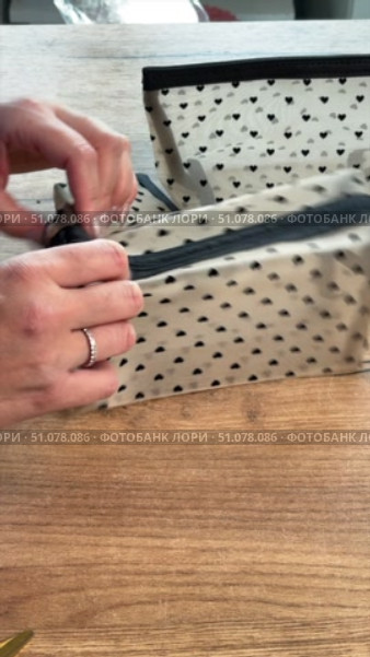 Woman reviewing set of three cosmetic bags in different sizes. Vertical video. Side Profile Shot. Close-up. Стоковое видео, видеограф Vadzim Yakubovich / Фотобанк Лори