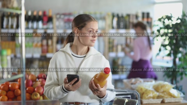 Woman scans the barcode of peach juice on her phone. Стоковое видео, видеограф Яков Филимонов / Фотобанк Лори