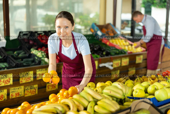 Woman selelr of vegetable department store is replenishing showcase with oranges. Стоковое фото, фотограф Яков Филимонов / Фотобанк Лори