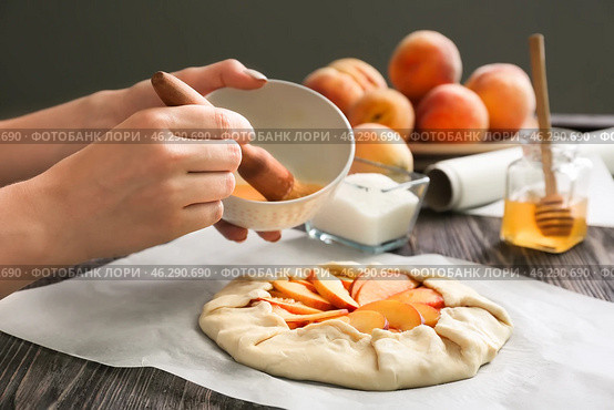 Woman smearing raw peach galette with egg yolk, closeup. Стоковое фото, фотограф Pixel_shot / Фотобанк Лори