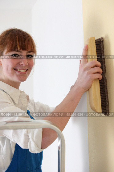Woman smoothing down wallpaper with a brush. Стоковое фото, агентство Ingram Publishing / Фотобанк Лори