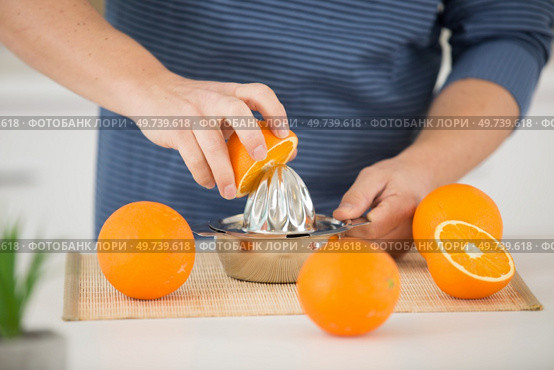 woman squeezing an orange fruit. Стоковое фото, агентство Ingram Publishing / Фотобанк Лори