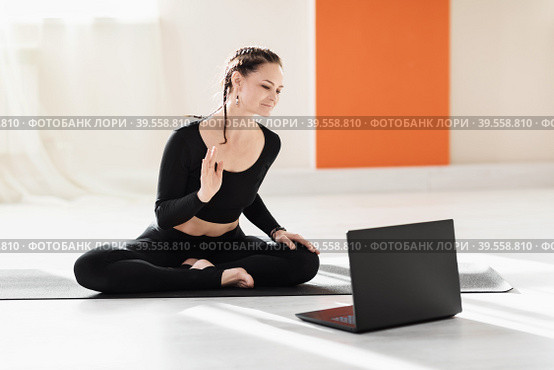 Woman universal yoga trainer greets pupils at the laptop before doing an online workout. Стоковое фото, фотограф Сергей Чайко / Фотобанк Лори