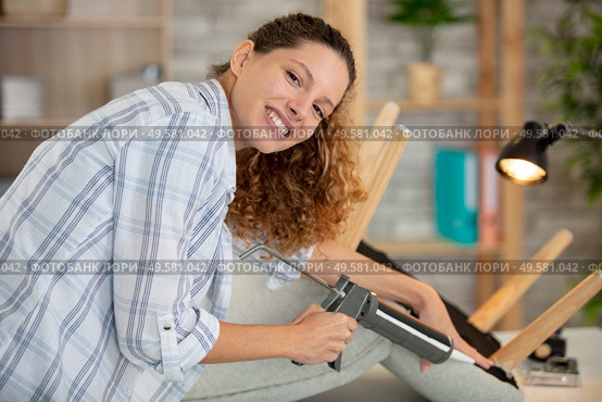 woman using sealant gun to repair a chair. Стоковое фото, агентство Ingram Publishing / Фотобанк Лори