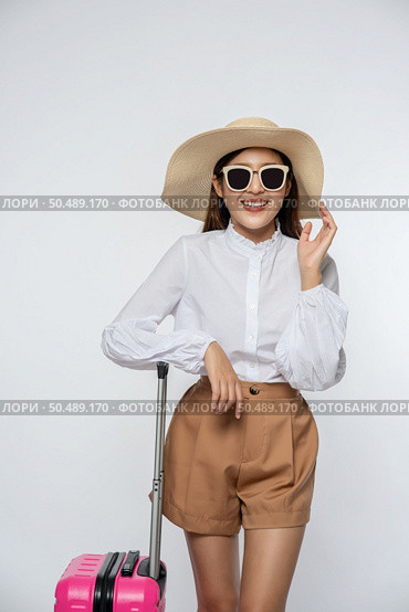 Woman wearing a hat, glasses, and handles of suitcases to travel. Стоковое фото, агентство Ingram Publishing / Фотобанк Лори