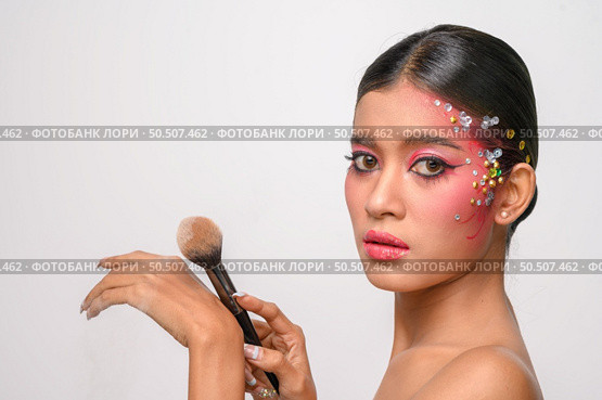 woman wearing pink makeup and holding a blush brush. Isolated on white background. Стоковое фото, агентство Ingram Publishing / Фотобанк Лори
