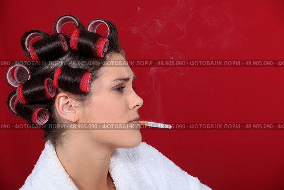 woman with hair curlers against red background smoking. Стоковое фото, агентство Ingram Publishing / Фотобанк Лори