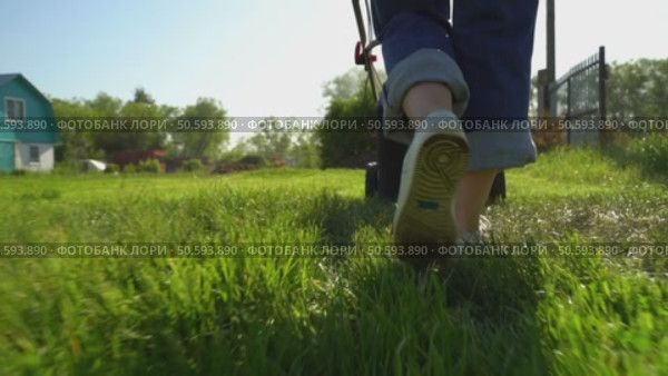 Woman with lawn mower in the garden. Стоковое видео, видеограф Igor Skripachev / Фотобанк Лори