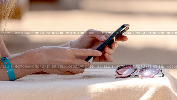 Woman with smartphone on a sun lounger on the beach by the sea. Стоковое фото, фотограф Igor Skripachev / Фотобанк Лори