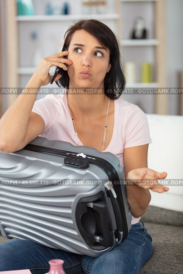 woman with suitcase on the telephone making questioning expression. Стоковое фото, агентство Ingram Publishing / Фотобанк Лори