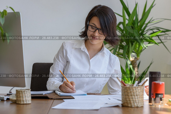 Woman writing at office during working day. Стоковое фото, агентство Ingram Publishing / Фотобанк Лори