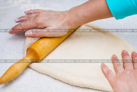 Woman's hands with a dough. A woman rolls out a piece of dough with a wooden rolling pin. Женские руки с тестом. Женщина раскатывает кусок теста деревянной скалкой. Стоковое фото, фотограф Дмитрий Березнев / Фотобанк Лори