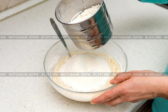 Woman's hands with an yeast dough. The woman is adding flour to the glass bowl with dough. Женские руки с дрожжевым тестом. Женщина насыпает муку в стеклянную миску с тестом. Стоковое фото, фотограф Дмитрий Березнев / Фотобанк Лори