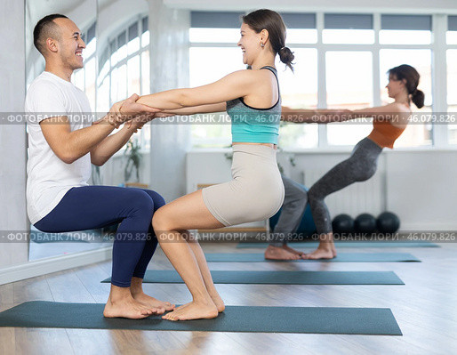 Women and men performing paired yoga exercises during group training at gym. Fitness and pair Hatha yoga concept. Стоковое фото, фотограф Яков Филимонов / Фотобанк Лори