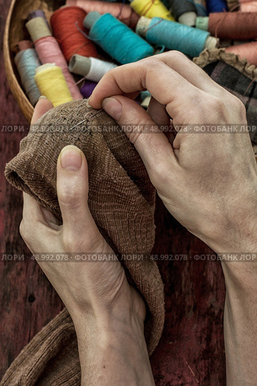 women's hands in the process stepania holey socks on the background of sewing thread. Стоковое фото, агентство Ingram Publishing / Фотобанк Лори