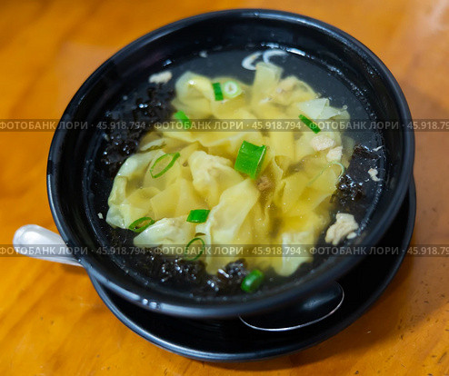 Wonton soup is cooked dumplings filled with meat or seafood. They are served in broth, usually enriched with onions and other ingredients. Chinese cuisine. Стоковое фото, фотограф Яков Филимонов / Фотобанк Лори