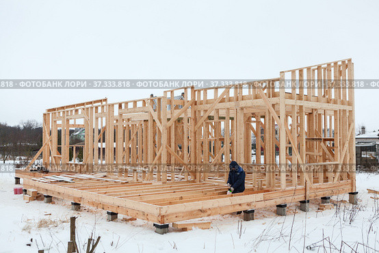 Wood frame house erection, bare frame with pile foundation, winter season, carpenter. Стоковое фото, фотограф Кекяляйнен Андрей / Фотобанк Лори