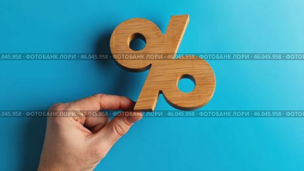 Wood percentage sign in a human hand. Blue studio background, copy space. Symbol percent. Seasonal sale, discount. Rate for finance, return. Investment ROI, credit, mortgage, tax, marketing, promotion. Стоковое AI-видео, аниматор Марина Демидюк / Фотобанк Лори