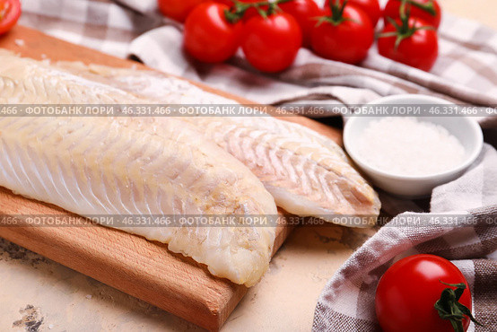Wooden board with raw codfish fillet on beige background. Стоковое фото, фотограф Pixel_shot / Фотобанк Лори