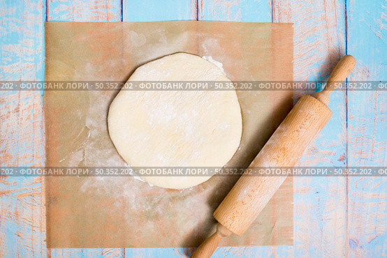 wooden rolling pin flat dough parchment paper wooden table. Стоковое фото, агентство Ingram Publishing / Фотобанк Лори