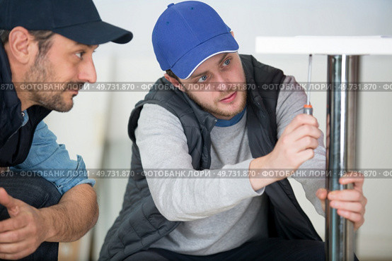 worker carpenter and his apprentice screwing chair leg. Стоковое фото, агентство Ingram Publishing / Фотобанк Лори