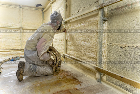 worker in a protective suit insulates the walls with polyurethane foam. Стоковое фото, фотограф Андрей Знаменский / Фотобанк Лори