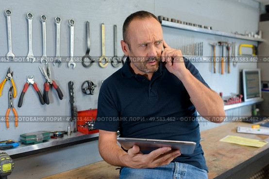 worker in an organize workshop talking on cellphone. Стоковое фото, агентство Ingram Publishing / Фотобанк Лори
