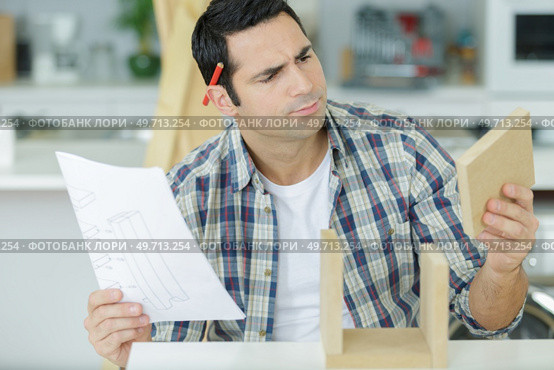 worker not sure about installing kitchen cupboard. Стоковое фото, агентство Ingram Publishing / Фотобанк Лори
