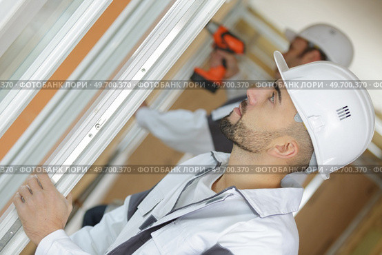 workmen fitting a window at a construction site. Стоковое фото, агентство Ingram Publishing / Фотобанк Лори