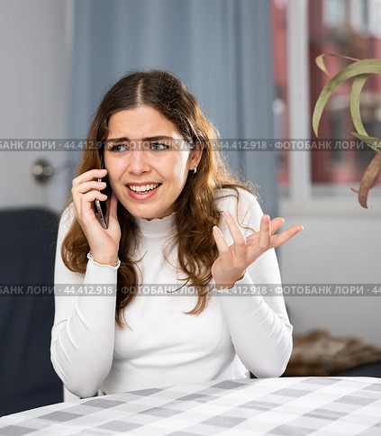 Wrathful woman quarreling on phone in apartment. Стоковое фото, фотограф Яков Филимонов / Фотобанк Лори