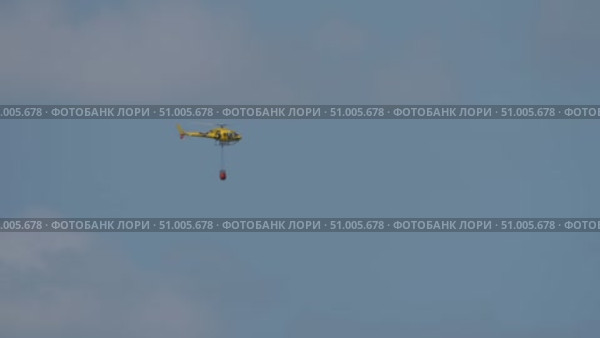 Yellow helicopter with red bambi bucket mid flight. Стоковое видео, видеограф Данил Руденко / Фотобанк Лори