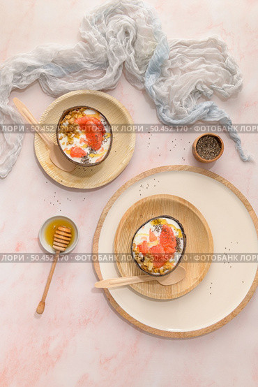 Yogurt with grapefruit, granola, chia and honey served in half a coconut shell on a rose marble kitchen countertop. Стоковое фото, агентство Ingram Publishing / Фотобанк Лори