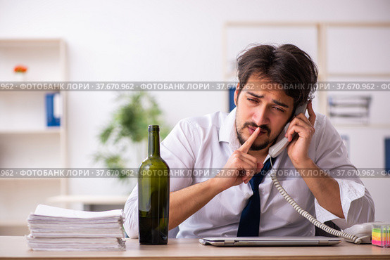 Young alcohol addicted employee sitting in the office. Стоковое фото, фотограф Elnur / Фотобанк Лори