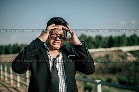 Young Asian Businessman wearing suit and tie with eyeglasses with problems and stress outside corporate office. Стоковое фото, агентство Ingram Publishing / Фотобанк Лори